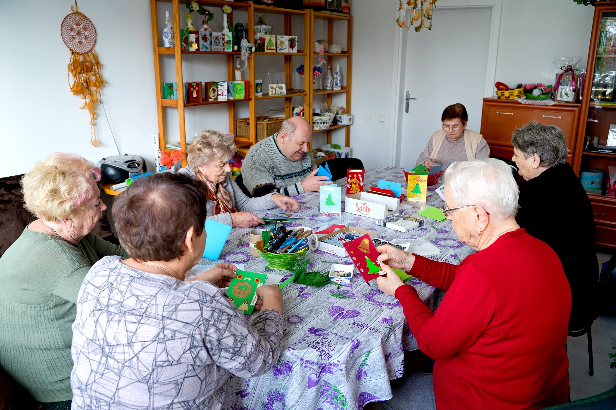 Na zdjęciu seniorzy siedzący przy stole i wykonujący kartki świąteczne.