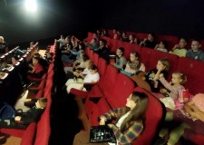 Powiększ zdjęcie Dzieci siedzą w kinie przed emisją filmu
