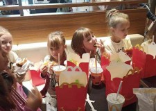 Powiększ zdjęcie dzieci siedzą przy stoliku zapełnionym przysmakami w McDonald 